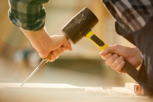 Closeup of unrecognizable carpenter hitting nail with hammer while working in joinery, copy space